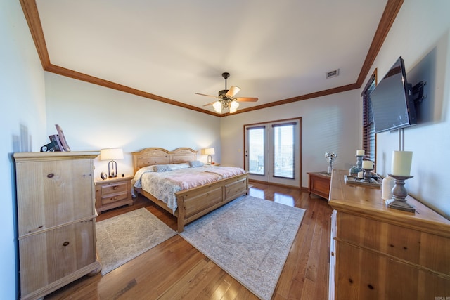 bedroom featuring crown molding, a ceiling fan, visible vents, and wood-type flooring