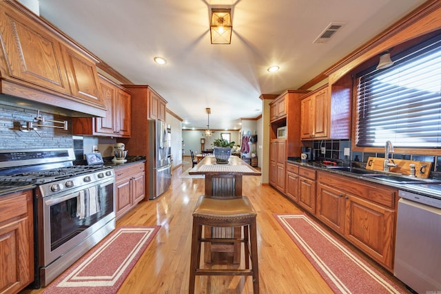 kitchen featuring brown cabinetry, visible vents, a sink, appliances with stainless steel finishes, and light wood-type flooring