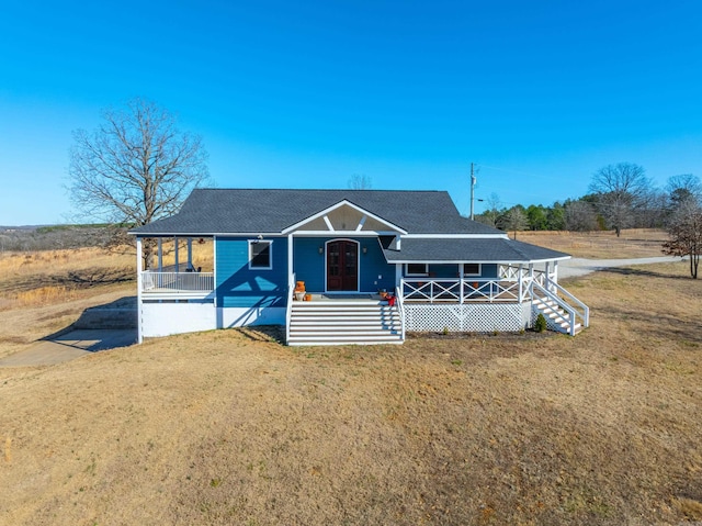 view of front of home featuring covered porch, a front yard, and roof with shingles