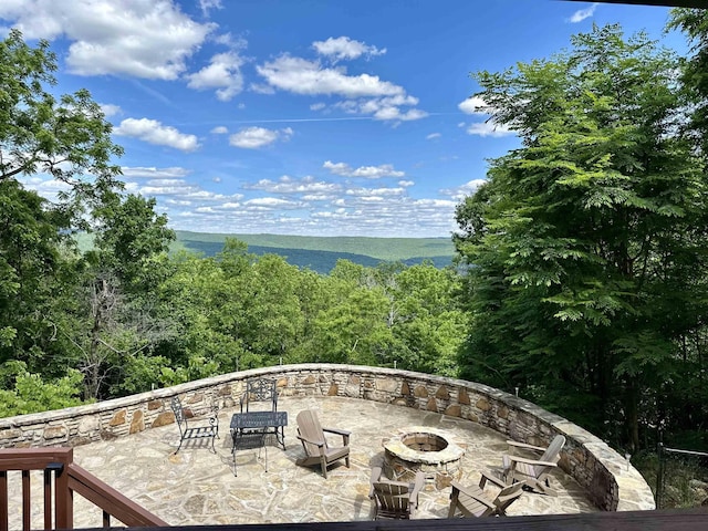 view of patio featuring an outdoor fire pit and a view of trees