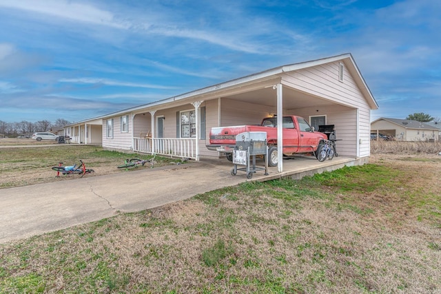 ranch-style home featuring a carport, concrete driveway, covered porch, and a front yard