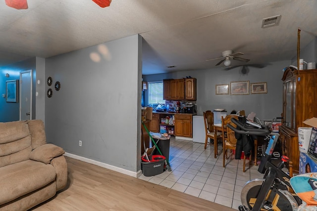 living room featuring visible vents, baseboards, ceiling fan, and light wood finished floors