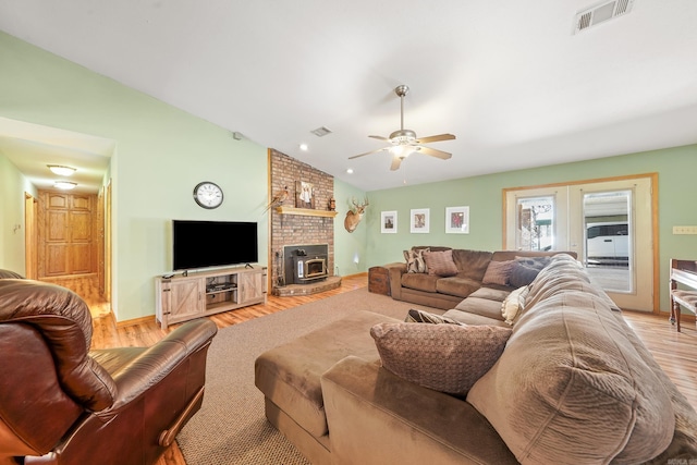 living room featuring light wood-type flooring, visible vents, ceiling fan, and vaulted ceiling