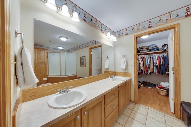 bathroom with a sink, a spacious closet, double vanity, and tile patterned flooring