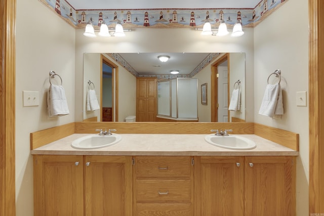 bathroom with double vanity, toilet, and a sink