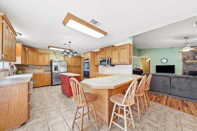 kitchen with visible vents, a sink, open floor plan, appliances with stainless steel finishes, and light countertops