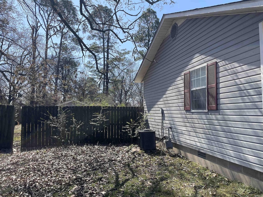 view of side of property with crawl space, central AC unit, and fence