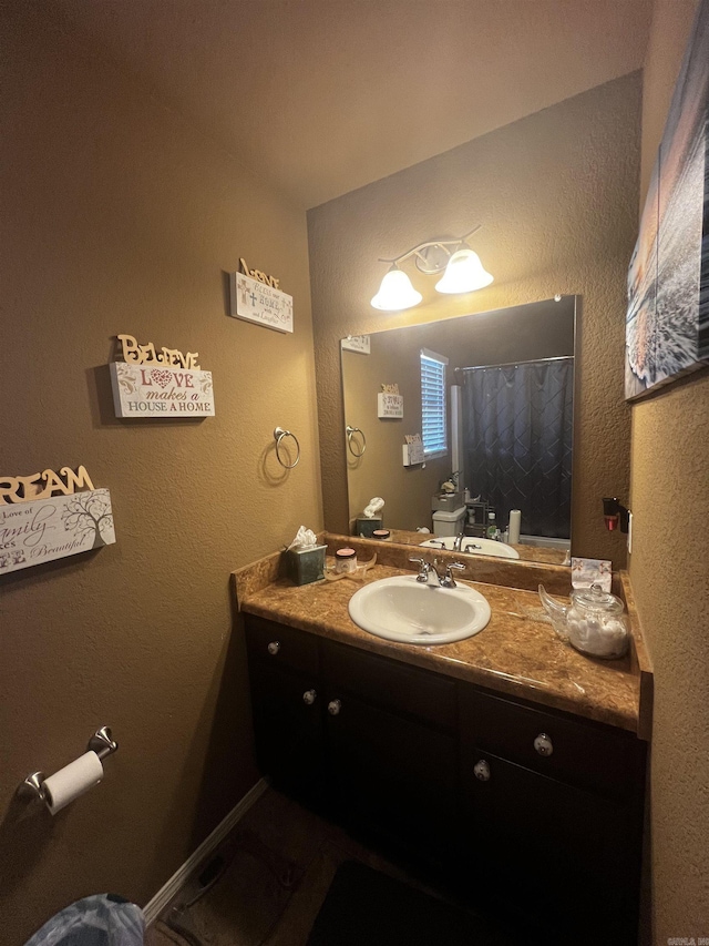 bathroom featuring a shower with curtain, toilet, vanity, and a textured wall