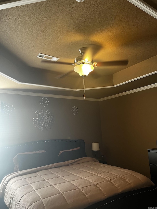 bedroom featuring a tray ceiling, crown molding, visible vents, and a textured ceiling