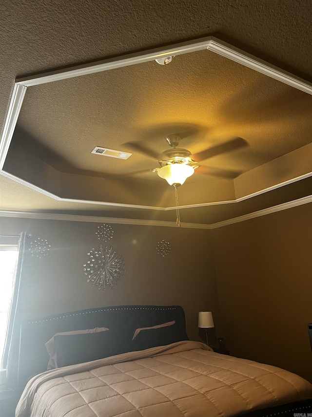 bedroom featuring visible vents, a textured ceiling, crown molding, and a tray ceiling