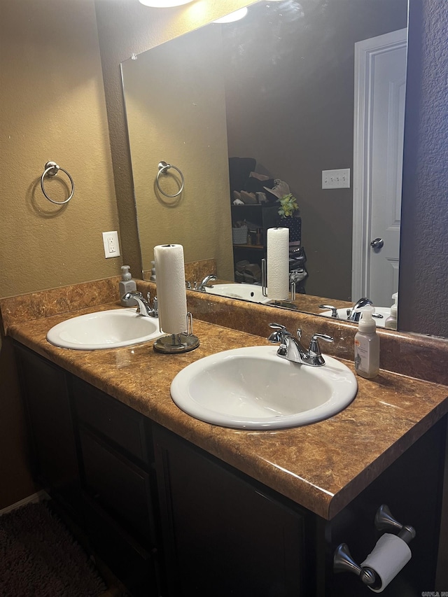 bathroom with double vanity, a textured wall, and a sink