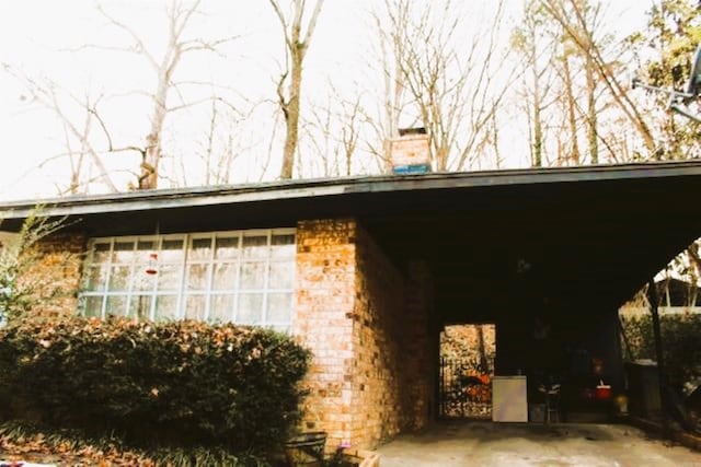 view of side of home featuring brick siding and a carport