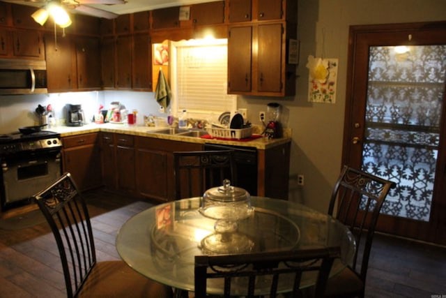 kitchen with ceiling fan, a sink, dark wood-type flooring, light countertops, and appliances with stainless steel finishes