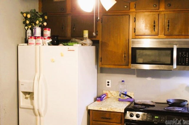 kitchen featuring stainless steel microwave, brown cabinets, electric range, and white refrigerator with ice dispenser