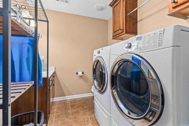 washroom featuring visible vents, baseboards, washer and clothes dryer, light tile patterned flooring, and cabinet space