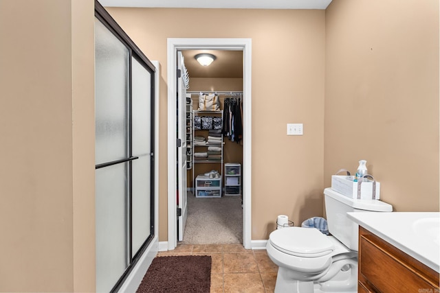 full bath with tile patterned floors, a walk in closet, toilet, a shower stall, and vanity