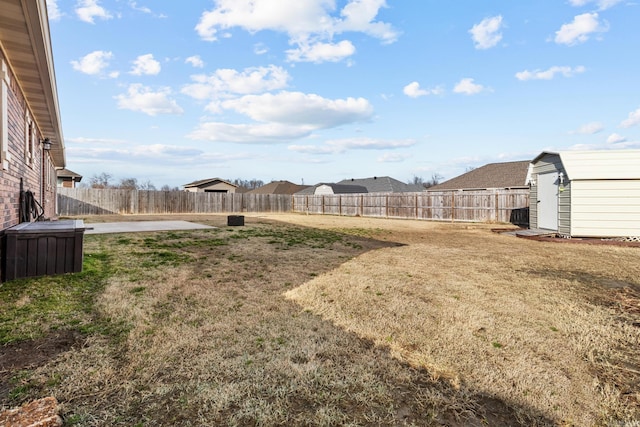 view of yard with an outbuilding, a fenced backyard, a shed, and a patio