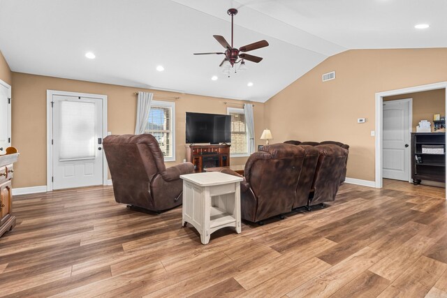 living area with lofted ceiling, visible vents, light wood-type flooring, and baseboards