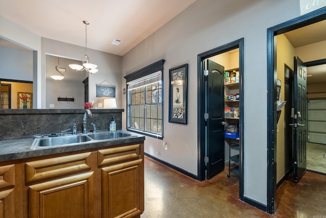 kitchen featuring visible vents, brown cabinets, a sink, dark countertops, and finished concrete floors