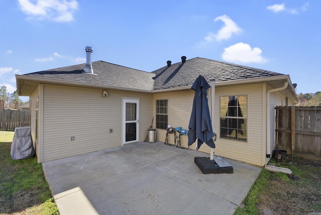 rear view of property featuring a patio area, fence, and a shingled roof