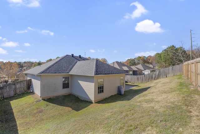 rear view of property with a lawn, a fenced backyard, and roof with shingles