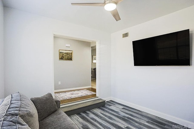 living area featuring visible vents, baseboards, a ceiling fan, and dark wood-style flooring