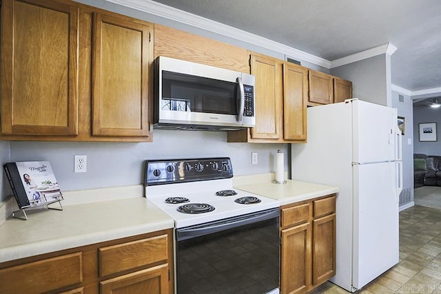 kitchen with freestanding refrigerator, light countertops, electric stove, crown molding, and stainless steel microwave