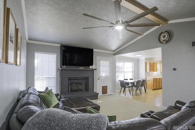 living area featuring a textured ceiling, vaulted ceiling with beams, a fireplace, and crown molding