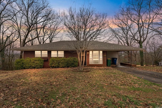 ranch-style house with brick siding, an attached carport, driveway, and a front lawn