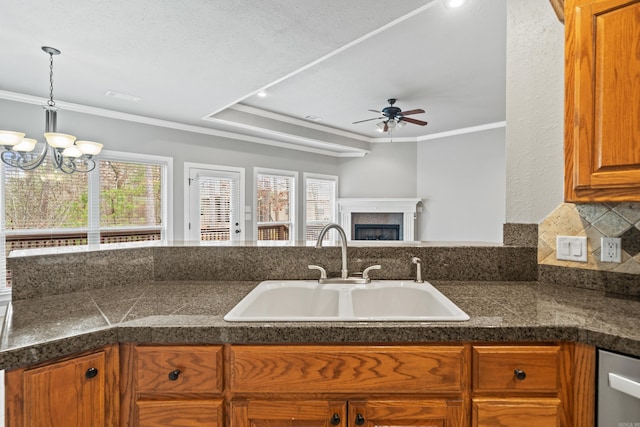 kitchen featuring a healthy amount of sunlight, ornamental molding, a fireplace, and a sink