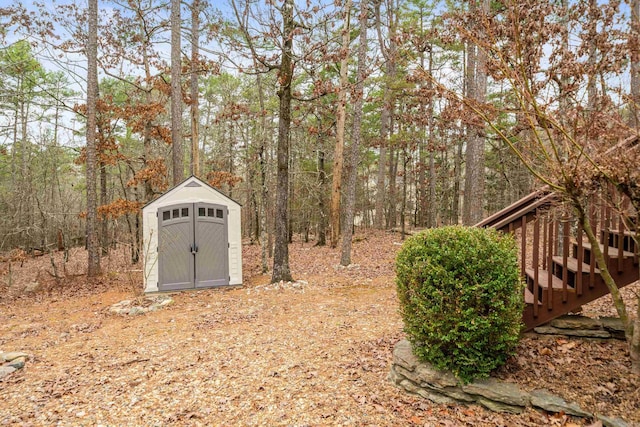 view of yard featuring a forest view, an outbuilding, and a shed