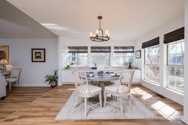 dining room with light wood-type flooring, visible vents, baseboards, and an inviting chandelier