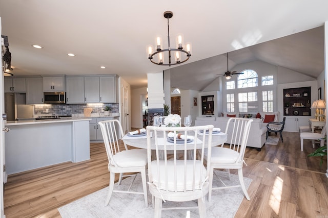 dining room with recessed lighting, lofted ceiling, ceiling fan with notable chandelier, and light wood finished floors