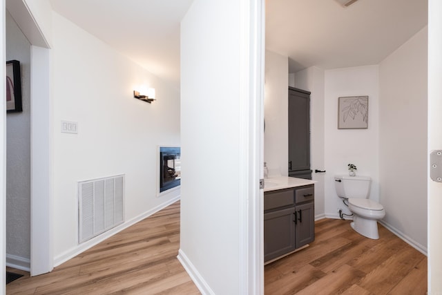 bathroom with vanity, wood finished floors, visible vents, baseboards, and toilet