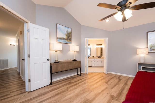 bedroom with light wood-type flooring, visible vents, baseboards, connected bathroom, and lofted ceiling