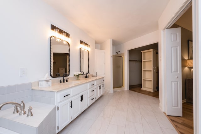 bathroom with a sink, a walk in closet, a stall shower, and double vanity