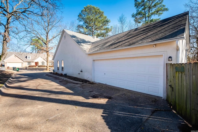 garage featuring driveway and fence