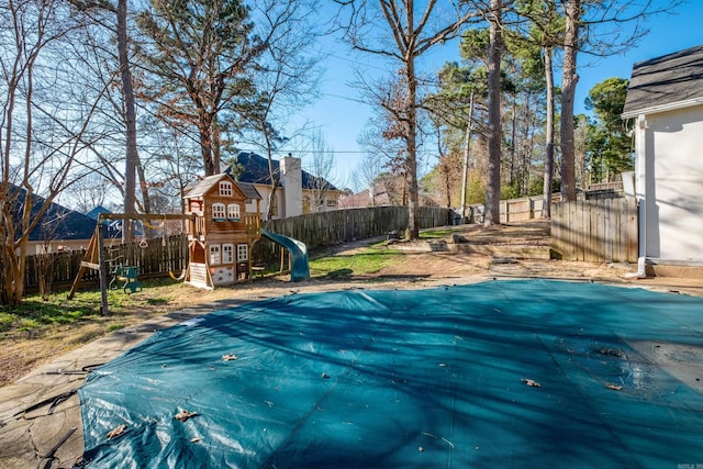 view of swimming pool featuring a playground, a fenced backyard, and a fenced in pool