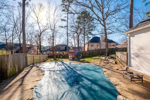 view of pool featuring a playground, a fenced backyard, and a residential view