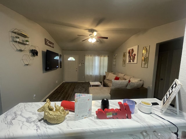 living area featuring baseboards, lofted ceiling, dark wood finished floors, and a ceiling fan