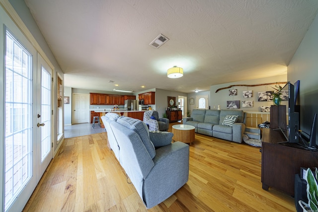 living area featuring visible vents, light wood-style floors, and french doors