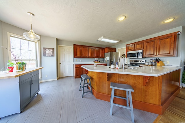 kitchen featuring a kitchen bar, stainless steel appliances, light countertops, and a sink