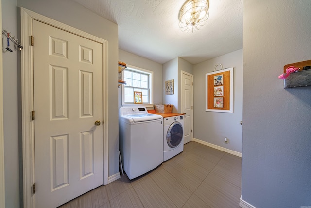 laundry area with washing machine and clothes dryer, laundry area, a textured ceiling, and baseboards