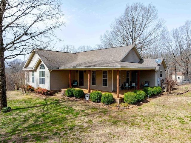 view of front facade with roof with shingles, covered porch, and a front lawn