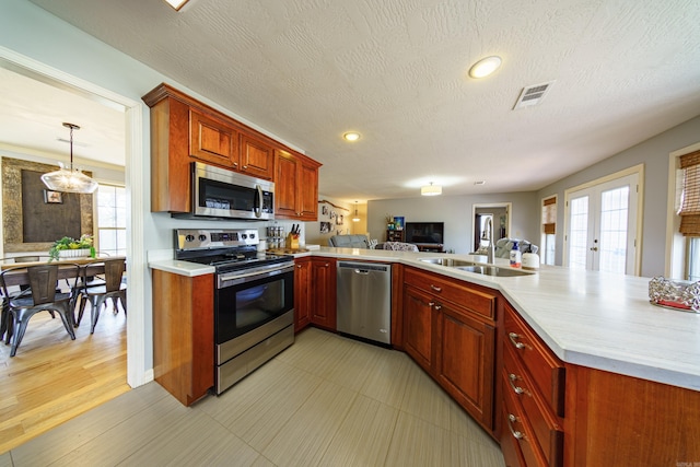 kitchen featuring open floor plan, light countertops, appliances with stainless steel finishes, a peninsula, and a sink