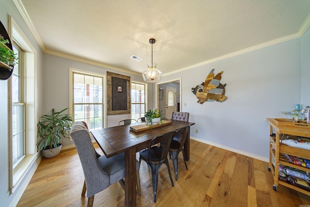 dining area featuring an inviting chandelier, crown molding, visible vents, and light wood finished floors