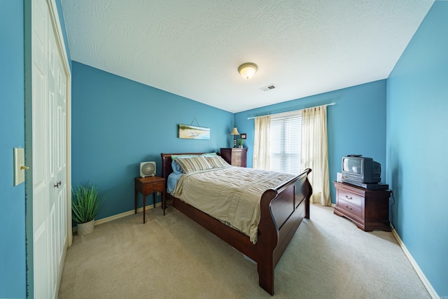 bedroom with visible vents, baseboards, light colored carpet, and a textured ceiling