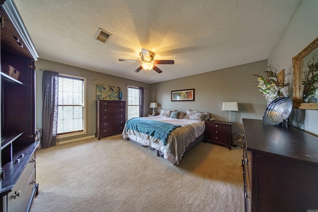 bedroom featuring light carpet, visible vents, a textured ceiling, and ceiling fan