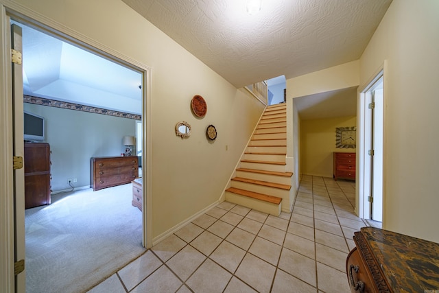 staircase with tile patterned floors, baseboards, a textured ceiling, and carpet flooring