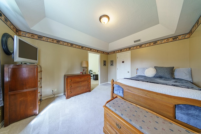 carpeted bedroom with a tray ceiling, baseboards, and visible vents